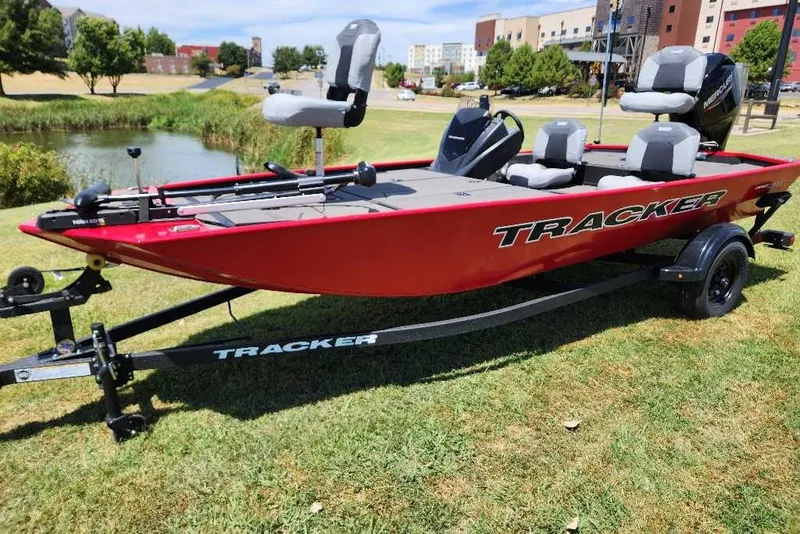 The Image of Red 2027 Tracker Pro 170 boat on trailer, parked on grass near a pond. - 0