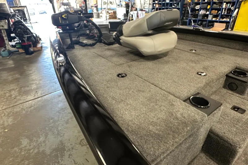 Slide: The Image of 2027 Tracker Pro Team 175 boat interior with gray carpet and seating in a workshop. - 62