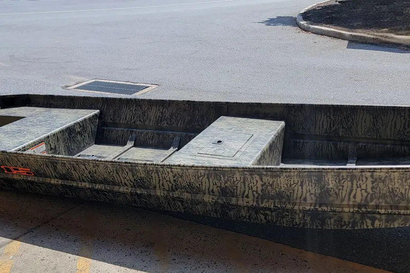 The Image of 2027 Tracker Grizzly 15 Jon boat with camouflage design on pavement. - 0