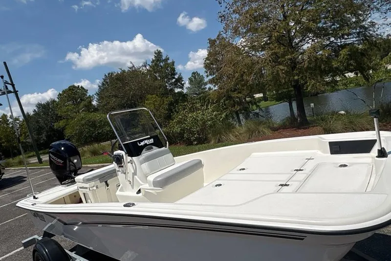 Slide: The Image of 2026 Mako Pro Skiff 15 CC boat parked near a scenic lake under a blue sky. - 8