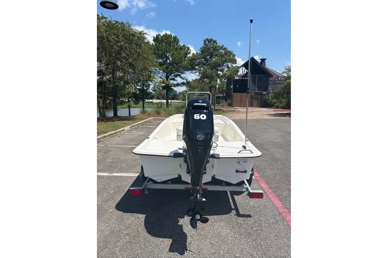 Slide: The Image of 2026 Mako Pro Skiff 15 CC boat with 60 HP motor in a parking lot. - 2