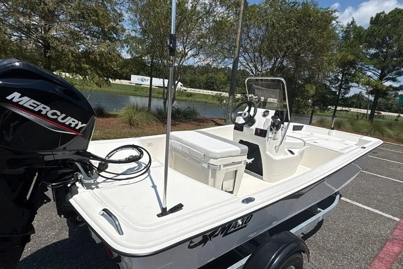 Slide: The Image of 2026 Mako Pro Skiff 15 CC boat with Mercury engine, parked near a lake. - 6