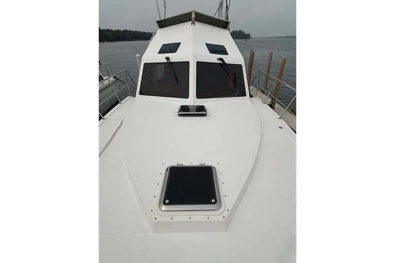 Slide: The Image of 2006 Island Pilot 395 boat docked, showcasing sleek white deck and cabin windows. - 3