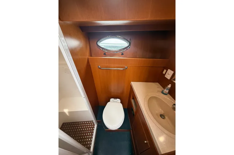 Slide: The Image of Bathroom interior of 2006 Island Pilot 395 yacht, featuring sink, toilet, and porthole window. - 35