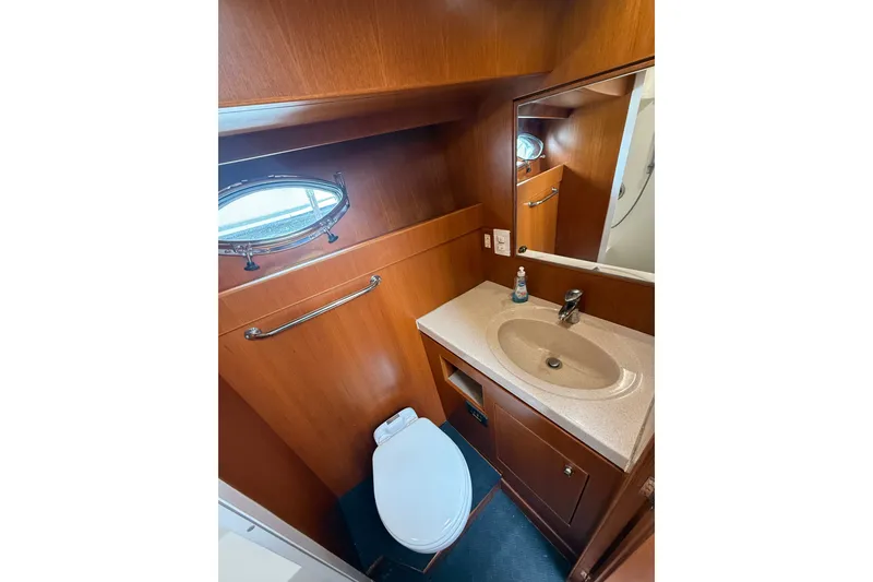 Slide: The Image of 2006 Island Pilot 395 yacht bathroom with wooden cabinetry, sink, and toilet. - 34