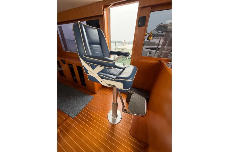 Slide: The Image of Captain's chair in 2006 Island Pilot 395 yacht interior, featuring wood flooring and large windows. - 26