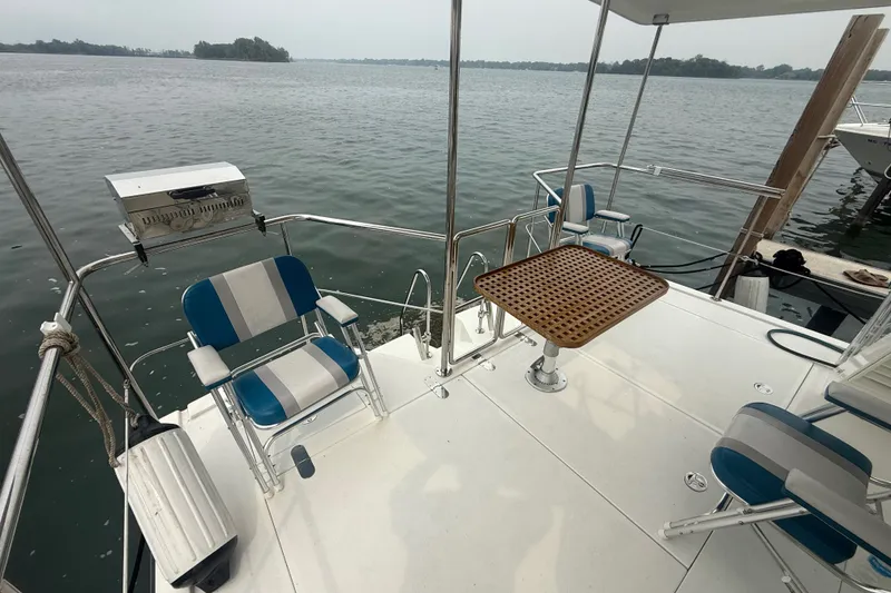 Slide: The Image of 2006 Island Pilot 395 boat deck with chairs, table, and grill by the water. - 9