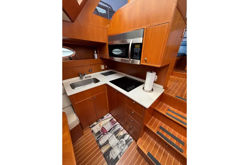 Slide: The Image of 2006 Island Pilot 395 yacht kitchen with wood cabinetry, sink, stove, and microwave. - 31