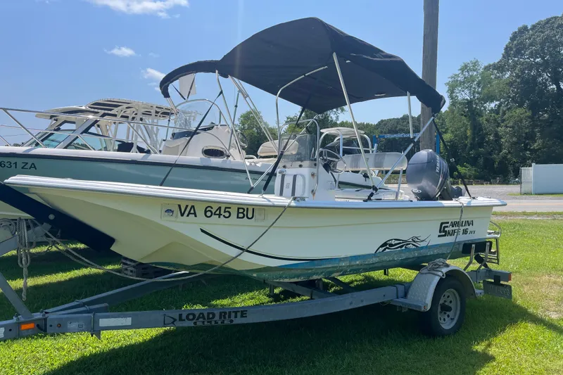 Slide: The Image of 2011 Carolina Skiff JVX16CC boat on trailer with canopy, parked on grass. - 15