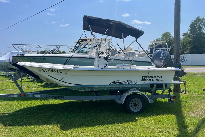 The Image of 2011 Carolina Skiff JVX16CC boat on trailer, parked on grass under clear sky. - 0