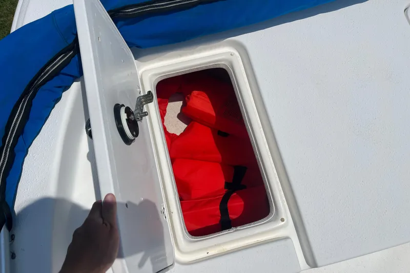 Slide: The Image of Open storage compartment on 2011 Carolina Skiff JVX16CC with red life jackets inside. - 13
