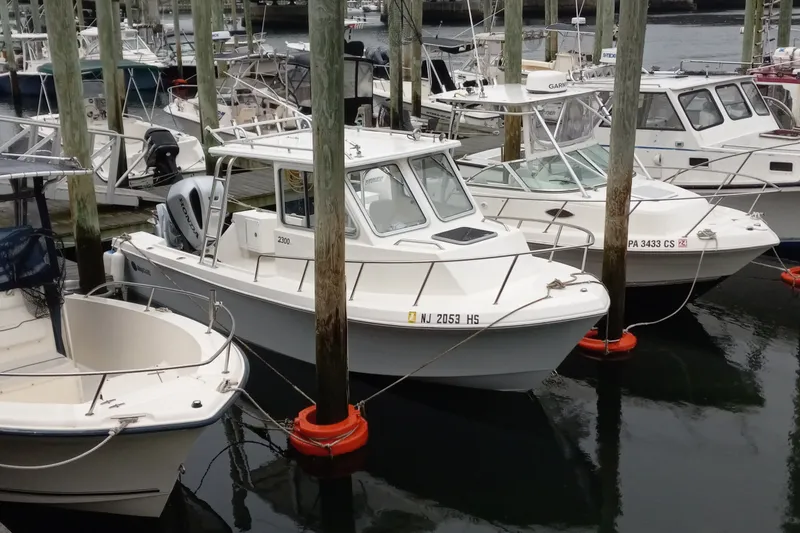 Slide: The Image of 2022 May-Craft 2300 Pilot House boat docked among other vessels at a marina. - 3
