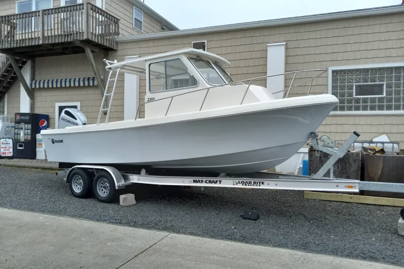 Slide: The Image of 2022 May-Craft 2300 Pilot House boat on trailer, parked near building. - 1