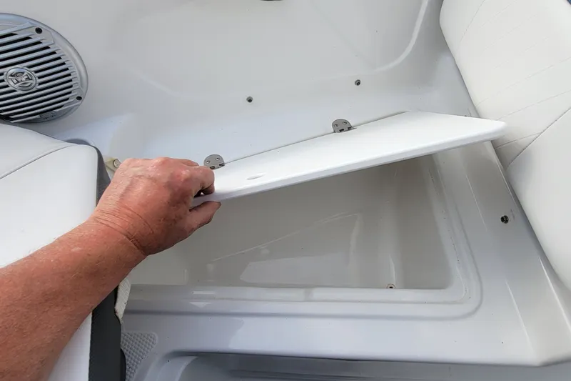 Slide: The Image of Hand opening storage compartment on 2022 Tahoe 185 S boat interior. - 33