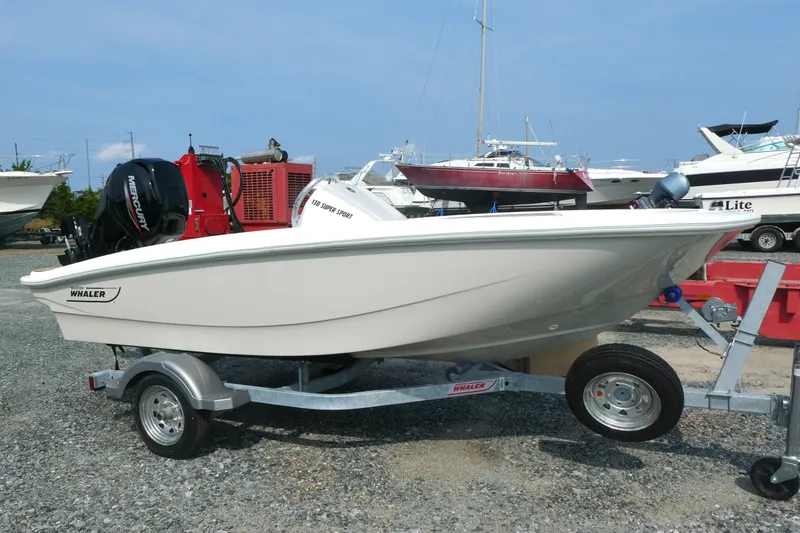Slide: The Image of 2027 Boston Whaler 130 Super Sport boat on trailer, parked outdoors. - 1