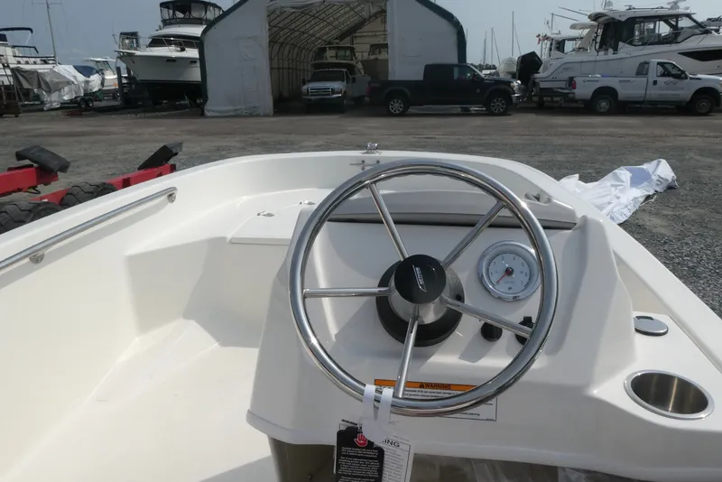 Slide: The Image of 2027 Boston Whaler 130 Super Sport boat dashboard with steering wheel and gauge. - 7