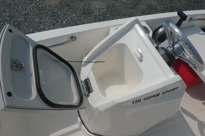 Slide: The Image of 2027 Boston Whaler 130 Super Sport boat interior with open storage compartment and steering wheel. - 6