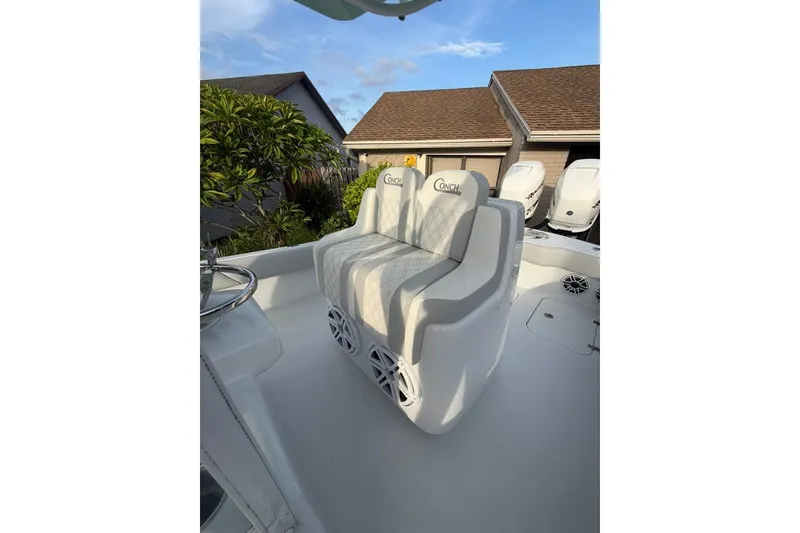 Slide: The Image of 2019 Conch 30 boat interior with cushioned seating and steering wheel, under a clear sky. - 14