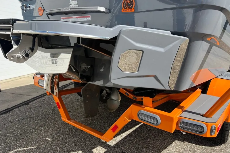 Slide: The Image of 2023 Malibu Wakesetter 22 LSV boat rear view with orange trailer and surf gate. - 10