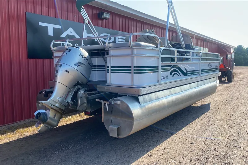 Slide: The Image of 2007 TMC 2200LE pontoon boat with Honda outboard motor, parked near a red building. - 8