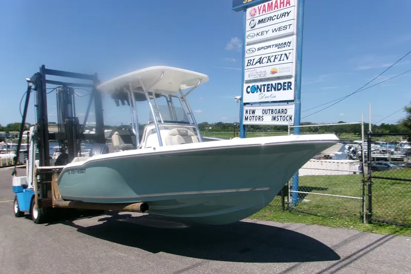 Slide: The Image of 2027 Key West 219 FS boat on forklift near dealership sign. - 2