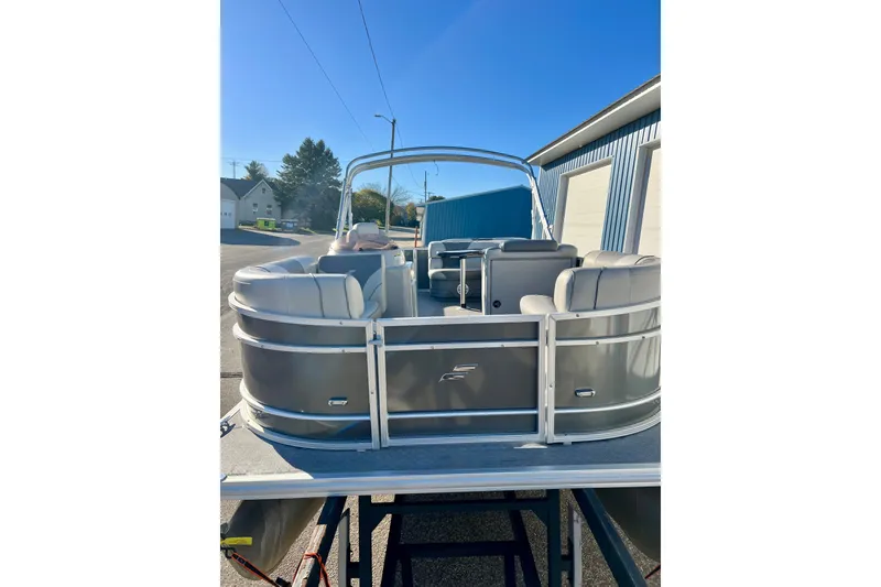 Slide: The Image of 2021 Starcraft EX 20 C pontoon boat with seating, parked outdoors under clear blue sky. - 25