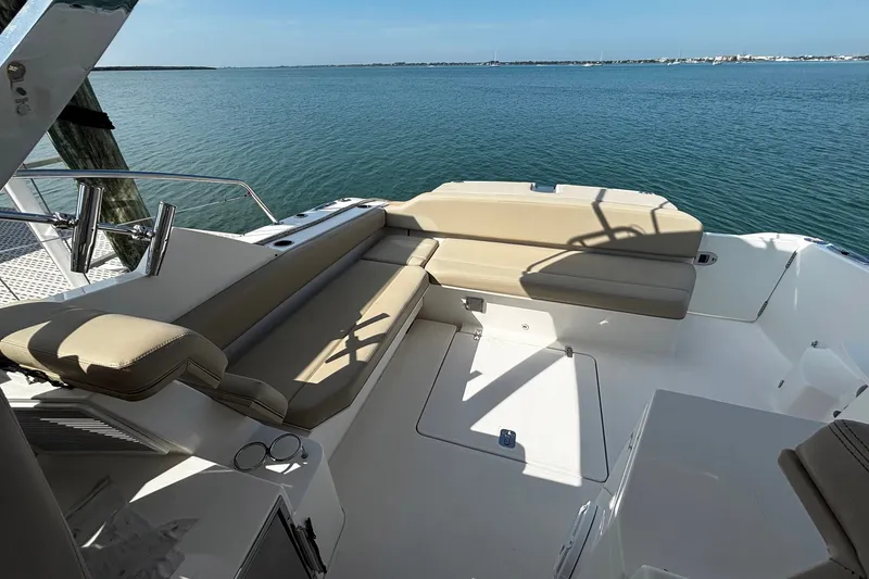 Slide: The Image of 2015 Pursuit SC 365i Sport Coupe boat interior with beige seating, overlooking calm waters. - 24