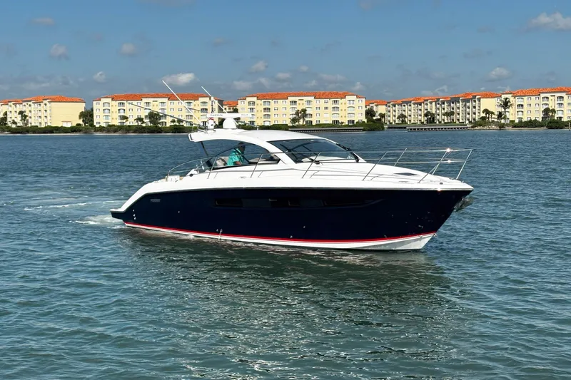 Slide: The Image of 2015 Pursuit SC 365i Sport Coupe cruising on a sunny day near waterfront buildings. - 2