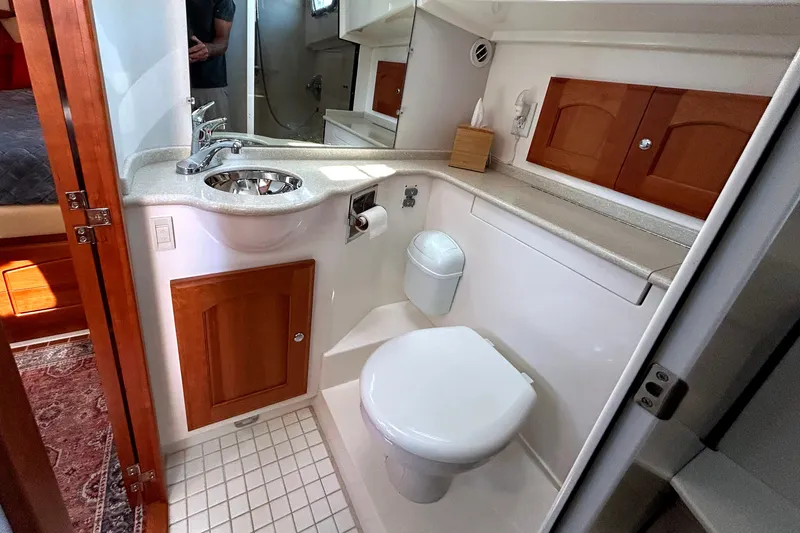 Slide: The Image of Compact bathroom in a 2007 Legacy 32 yacht, featuring a sink, toilet, and wooden cabinetry. - 24