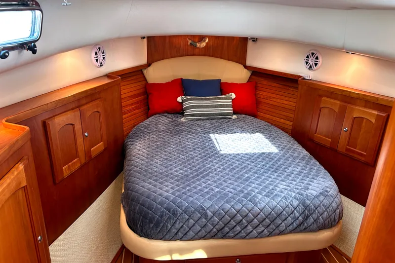 Slide: The Image of Cozy cabin interior of a 2007 Legacy 32 boat with a plush bed and wooden cabinetry. - 18