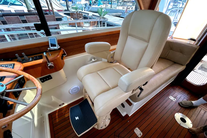 Slide: The Image of Captain's chair and helm in 2007 Legacy 32 yacht, featuring wood accents and navigation controls. - 13