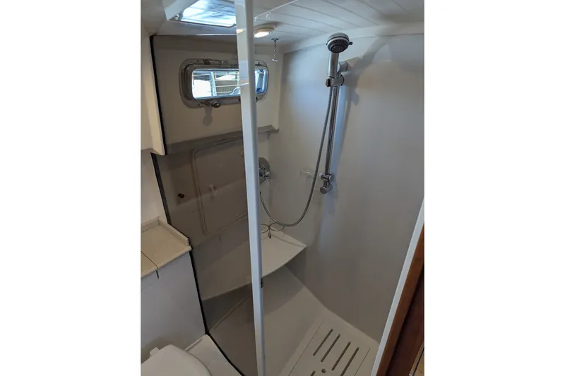 Slide: The Image of Compact shower area in a 2007 Legacy 32 boat, featuring modern fixtures and a window. - 25