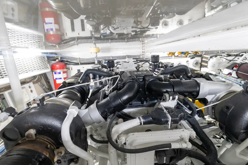 Slide: The Image of Engine room of a 2008 Hatteras 64 Motor Yacht, showcasing complex machinery and fire extinguishers. - 33