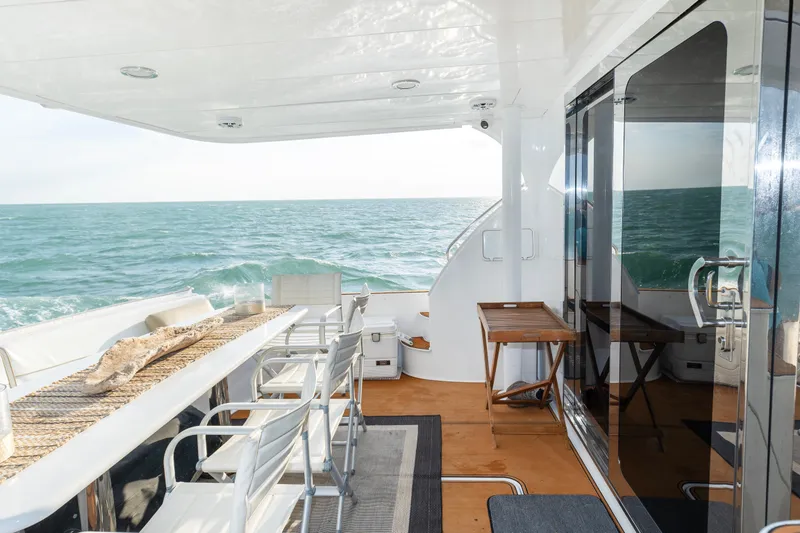 Slide: The Image of 2008 Hatteras 64 Motor Yacht deck with ocean view, featuring seating and table. - 18