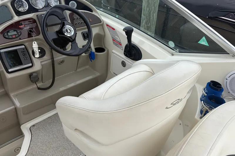 Slide: The Image of 2005 Sea Ray Sundancer 260 helm with steering wheel, controls, and white seating. - 14