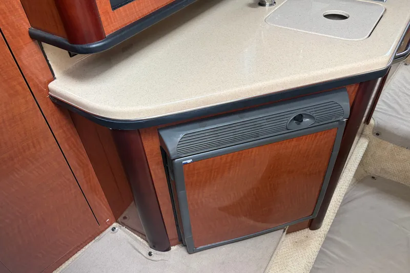 Slide: The Image of 2005 Sea Ray Sundancer 260 interior with compact kitchenette and wood finish. - 25