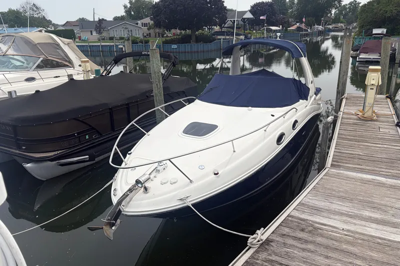 The Image of 2005 Sea Ray Sundancer 260 docked at a marina, featuring sleek design and covered cockpit. - 0
