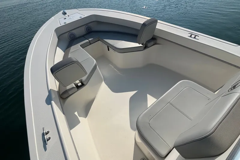 Slide: The Image of 2023 May-Craft 2300 CCX boat interior with cushioned seating on calm water. - 6