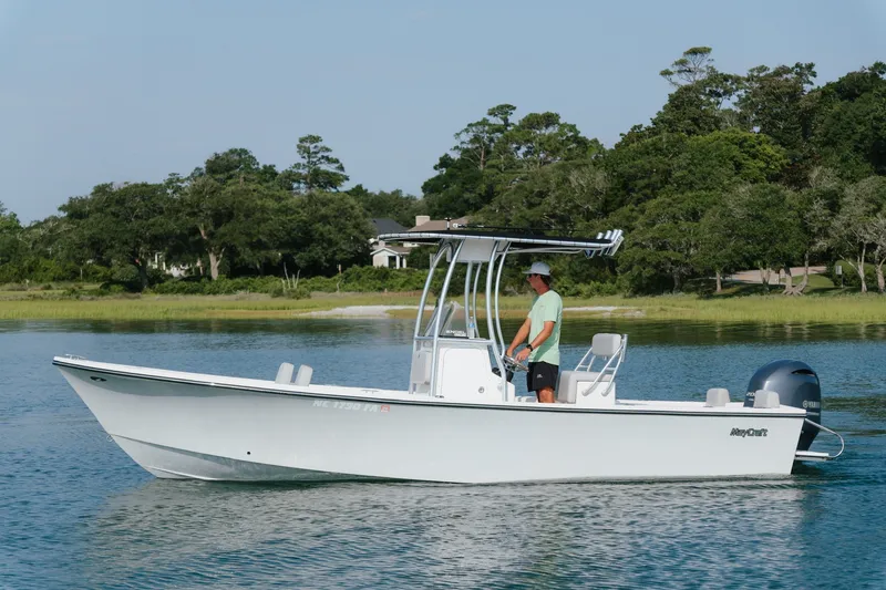 The Image of 2023 May-Craft 2300 CCX boat on calm water with lush green shoreline. - 0