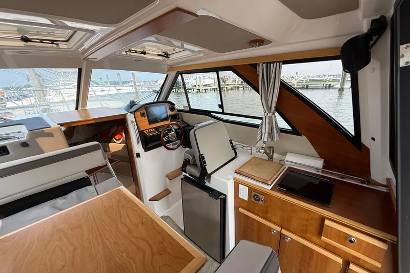 Slide: The Image of 2024 Cutwater C-248 Coupe interior with helm, seating, and kitchenette, docked at marina. - 36