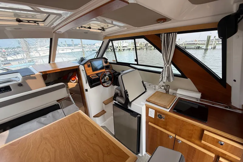 Slide: The Image of 2024 Cutwater C-248 Coupe interior with helm, kitchenette, and marina view. - 35
