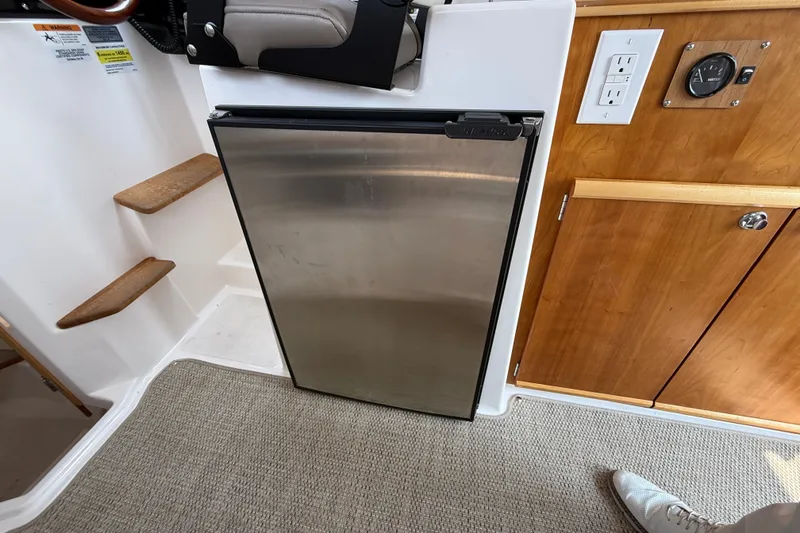Slide: The Image of 2024 Cutwater C-248 Coupe interior with stainless steel fridge and wooden cabinetry. - 25