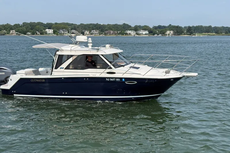 Slide: The Image of 2024 Cutwater C-248 Coupe cruising on a calm lake with scenic shoreline. - 2