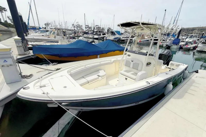 The Image of 2024 Mako 214 Center Console boat docked in a marina, surrounded by other vessels. - 0