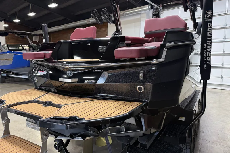 Slide: The Image of 2023 MasterCraft XStar S boat with red seats and teak swim platform in showroom. - 26