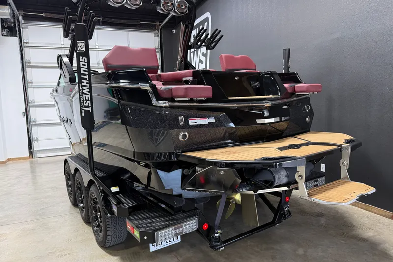 Slide: The Image of 2023 MasterCraft XStar S boat with maroon seats and sleek black exterior in a showroom. - 24