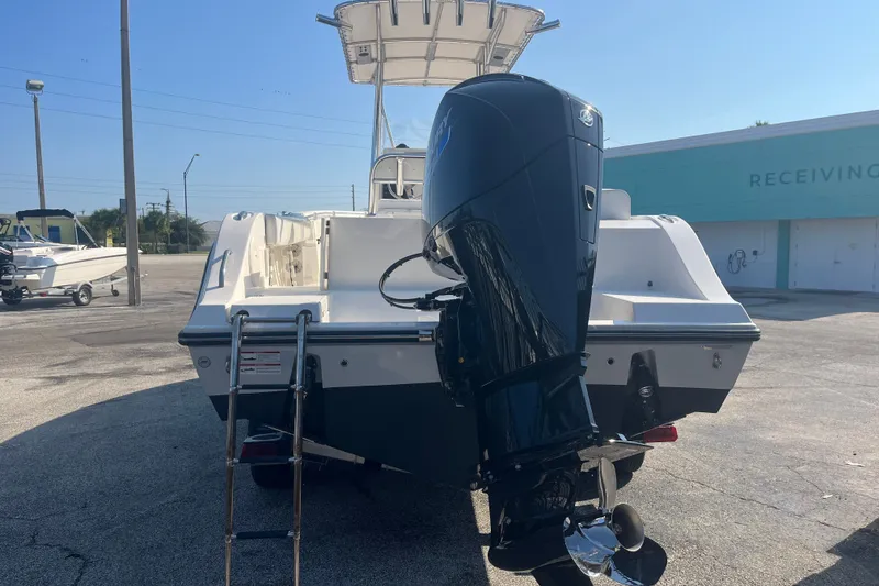 Slide: The Image of 2024 Cobia 237 Center Console boat with outboard motor and ladder, parked outdoors. - 6
