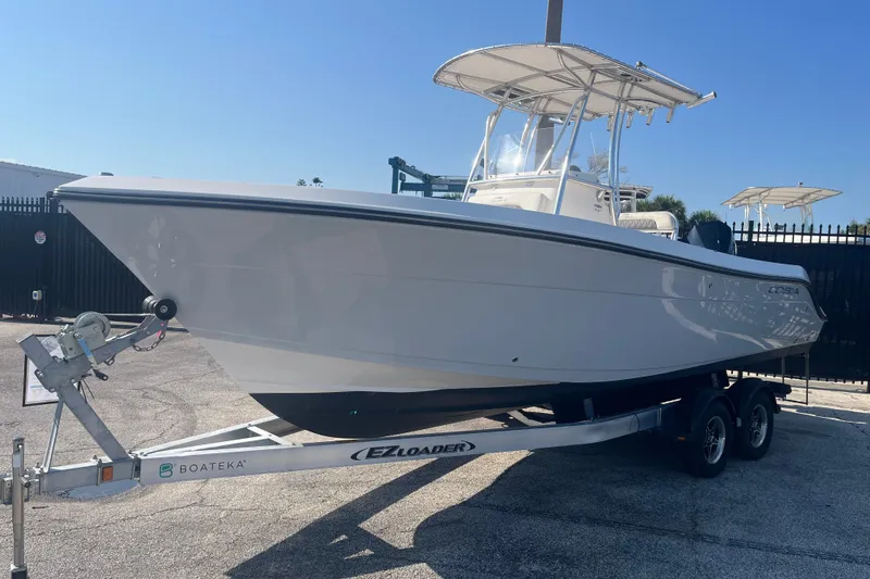 Slide: The Image of 2024 Cobia 237 Center Console boat on trailer, parked outdoors under clear sky. - 4