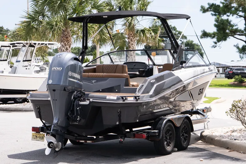 Slide: The Image of 2023 Glastron GX 210 boat with Yamaha engine, parked on trailer, surrounded by palm trees. - 6