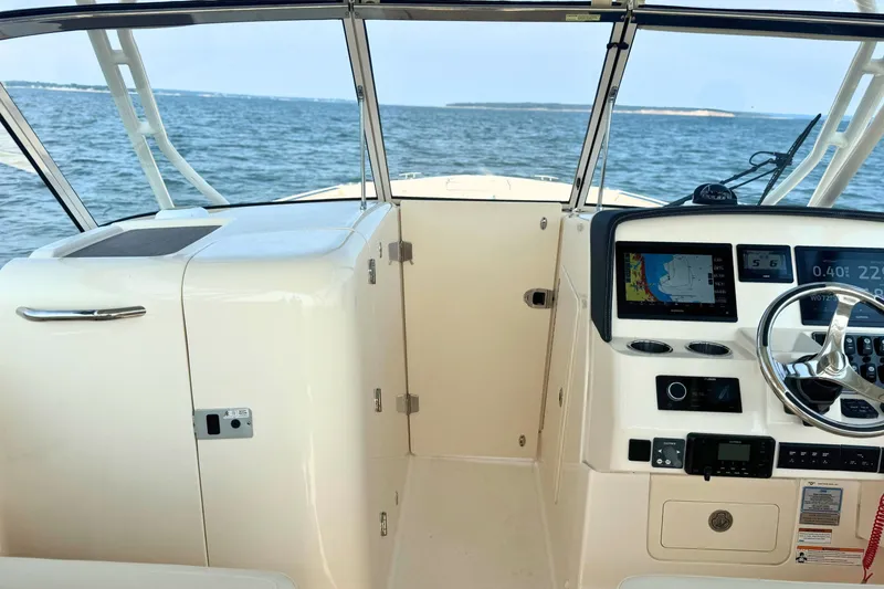 Slide: The Image of 2023 Grady-White Freedom 285 boat cockpit with navigation system, steering wheel, and ocean view. - 31